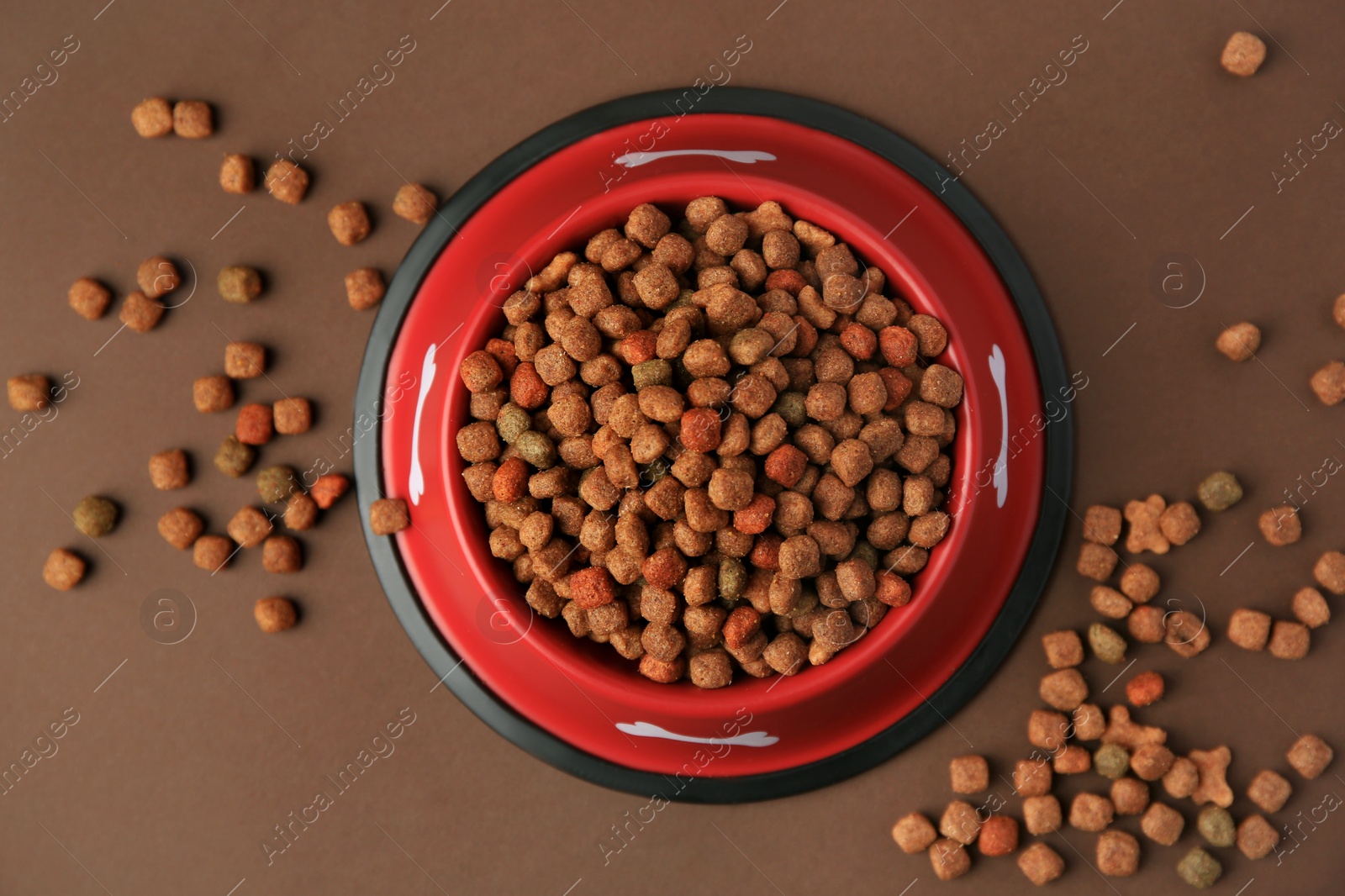 Photo of Dry dog food and feeding bowl on brown background, flat lay