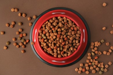 Photo of Dry dog food and feeding bowl on brown background, flat lay