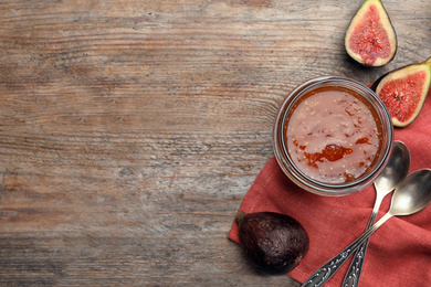 Photo of Homemade delicious fig jam on wooden table, flat lay. Space for text