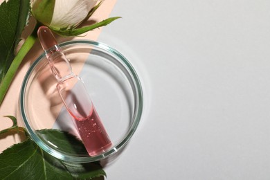 Photo of Pharmaceutical ampoule with medication and flower on light background, flat lay. Space for text