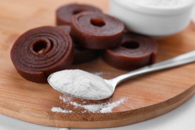 Sweet fructose powder and fruit leather rolls on wooden table, closeup