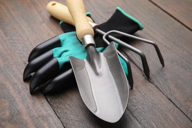 Claw gardening gloves, trowel and rake on wooden table