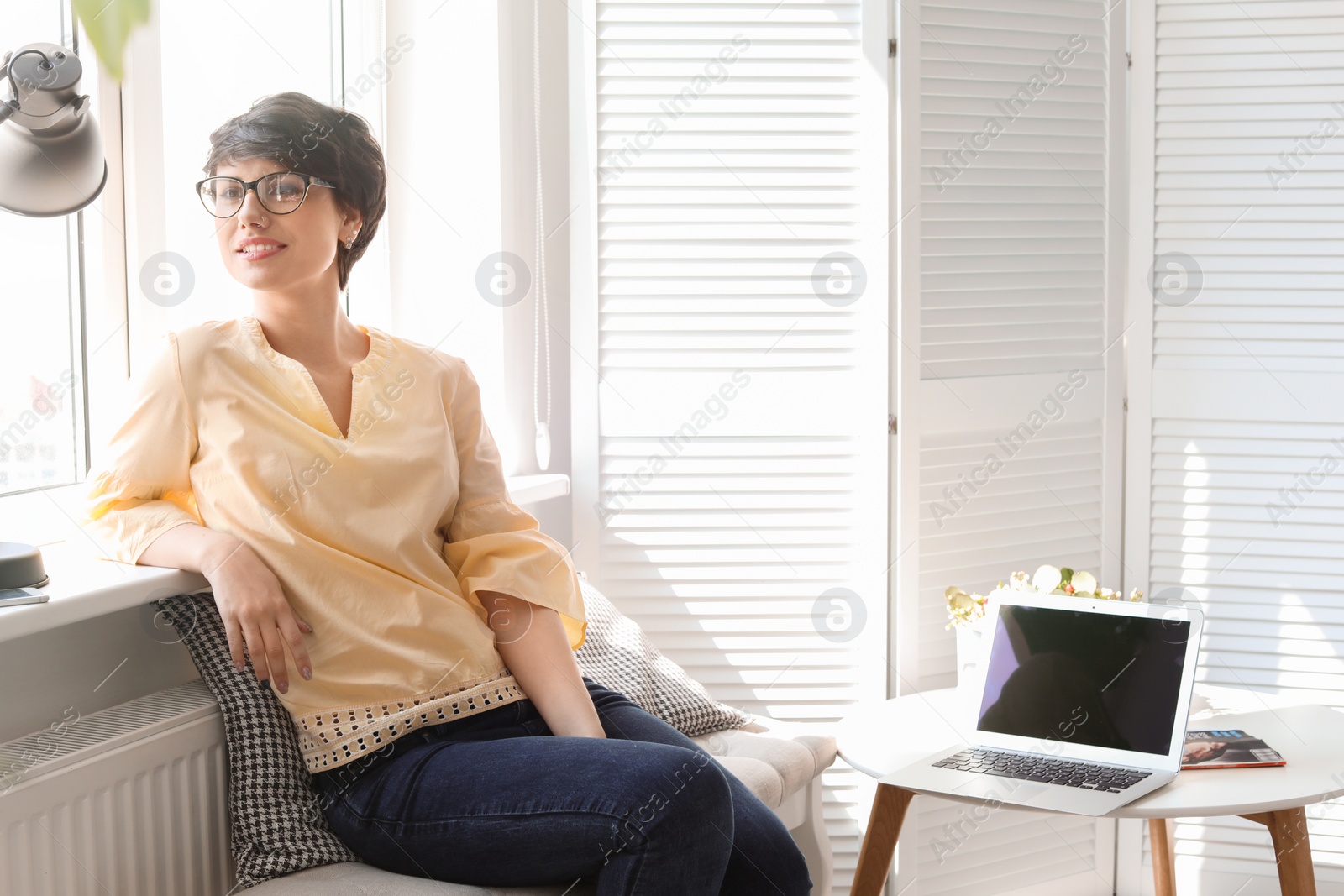 Photo of Young woman sitting near window at home