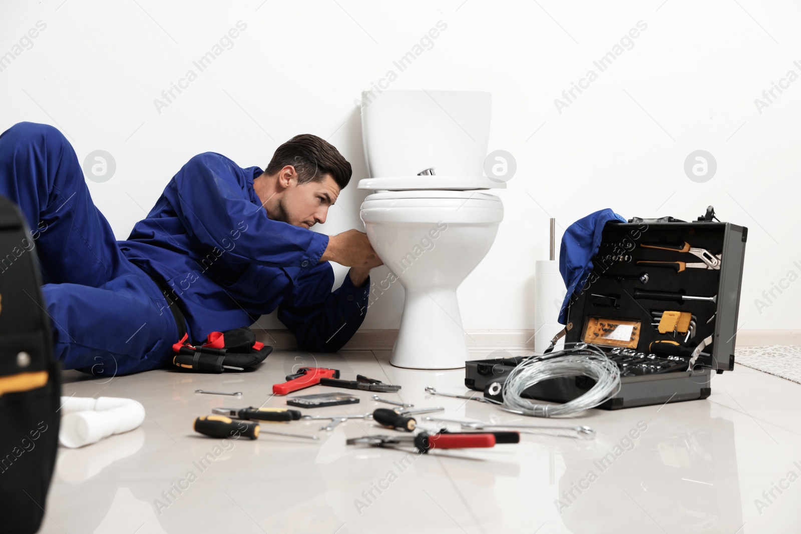 Photo of Professional plumber working with toilet bowl in bathroom