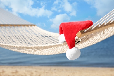 Photo of Rope hammock with Santa's hat on beach, closeup. Christmas vacation