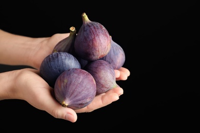 Photo of Woman holding fresh ripe figs on black background