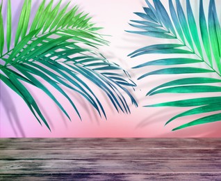 Palm branches and wooden table against light background, color tone effect. Summer party