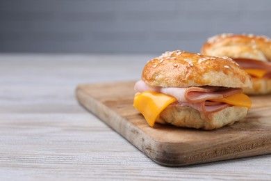Photo of Delicious bagels with ham and cheese on light wooden table. Space for text