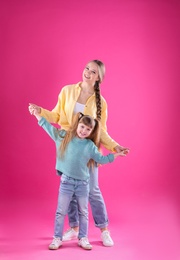 Happy woman and daughter in stylish clothes on color background