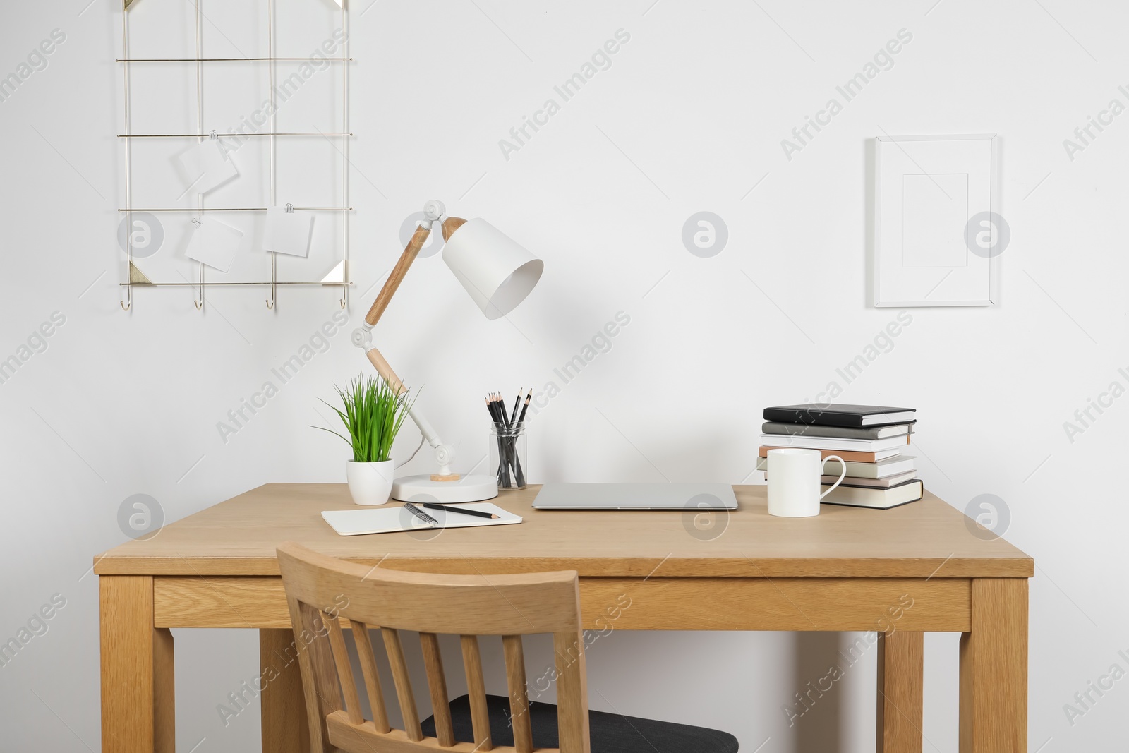 Photo of Cozy workspace with laptop, lamp and stationery on wooden desk at home