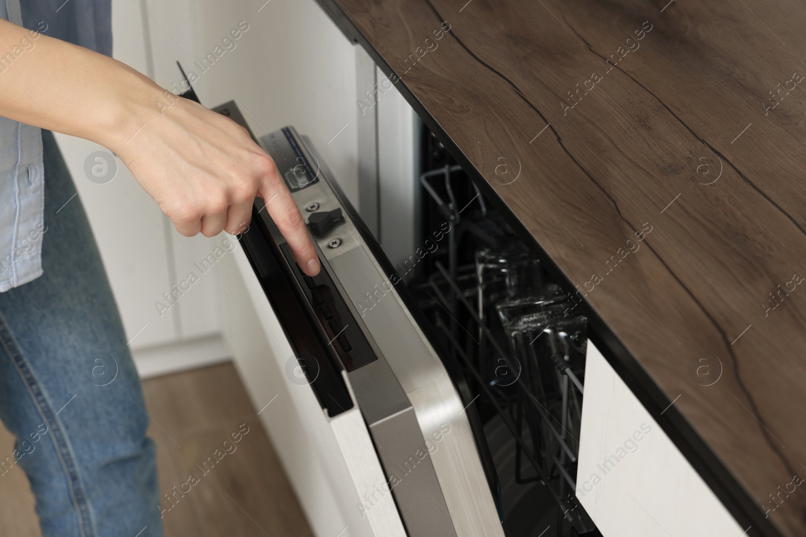 Photo of Woman pushing button on dishwasher's door indoors, closeup