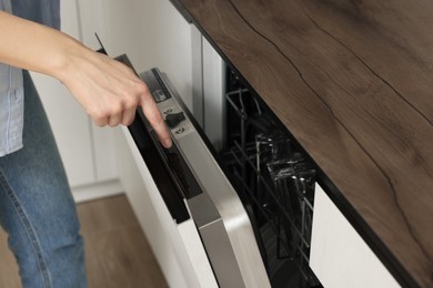 Photo of Woman pushing button on dishwasher's door indoors, closeup