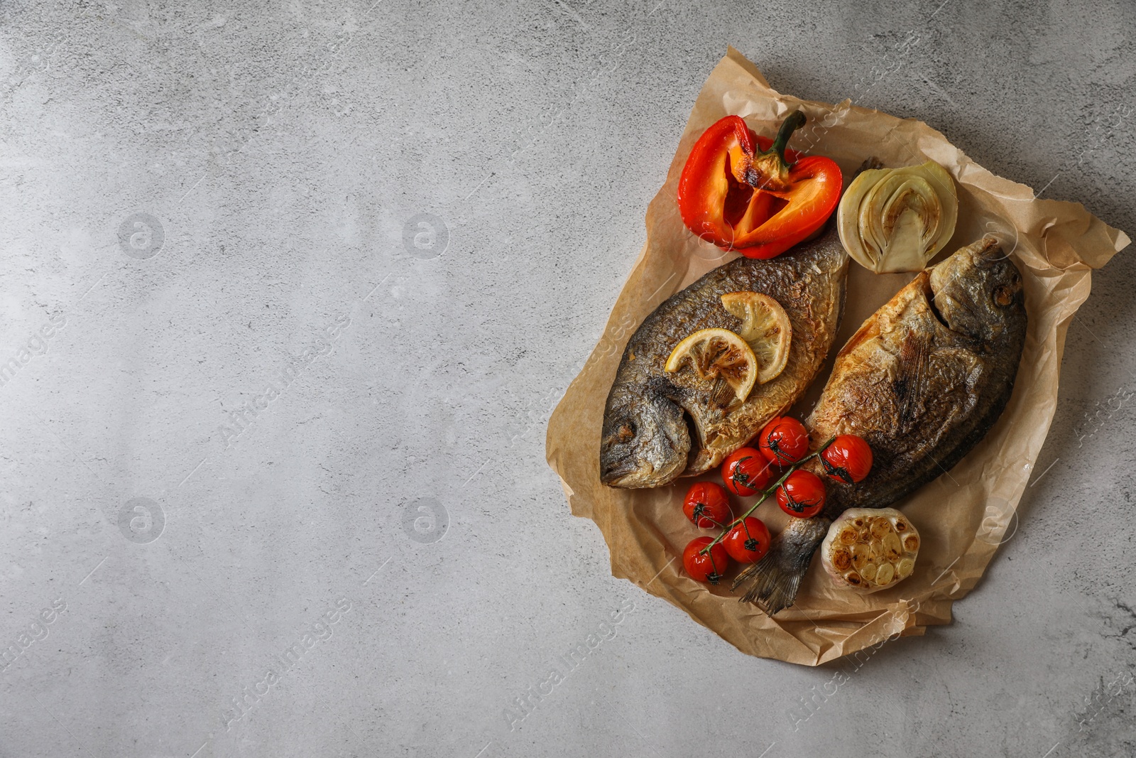 Photo of Delicious dorado fish with vegetables served on light grey table, top view. Space for text