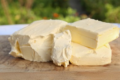 Board with tasty homemade butter on wooden table outdoors, closeup