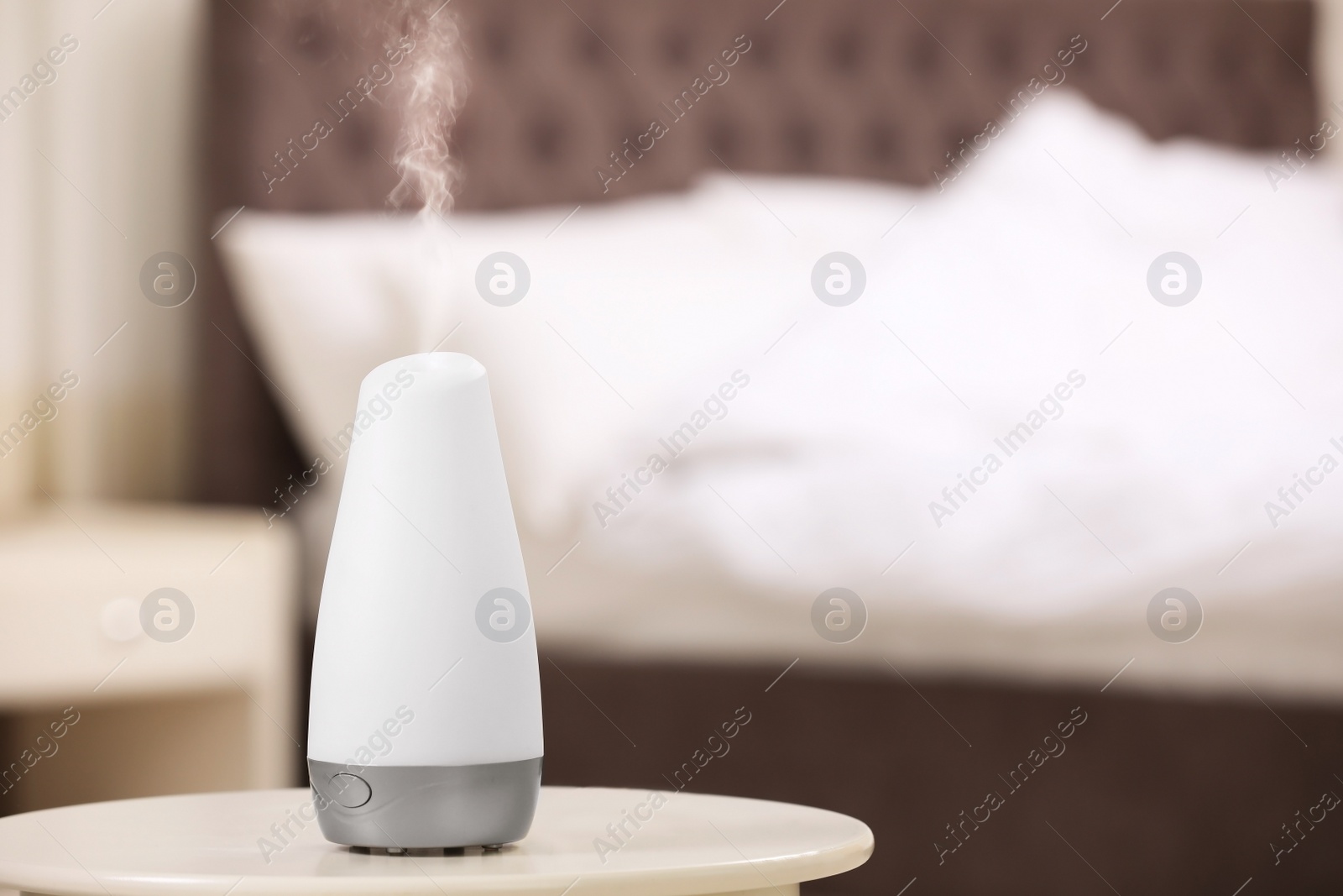 Photo of Modern essential oil diffuser on table indoors. Space for text