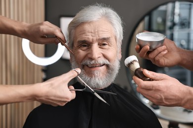 Professional barbers taking care of client's mustache and beard in barbershop