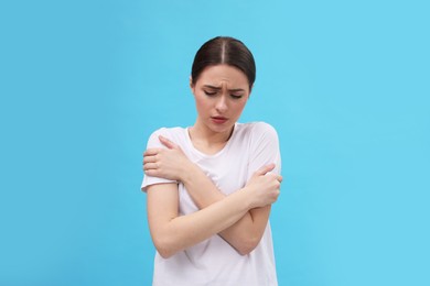 Photo of Woman suffering from fever on light blue background. Cold symptoms