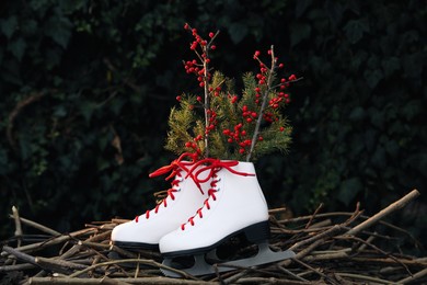 Pair of ice skates with Christmas decor on dry branches outdoors