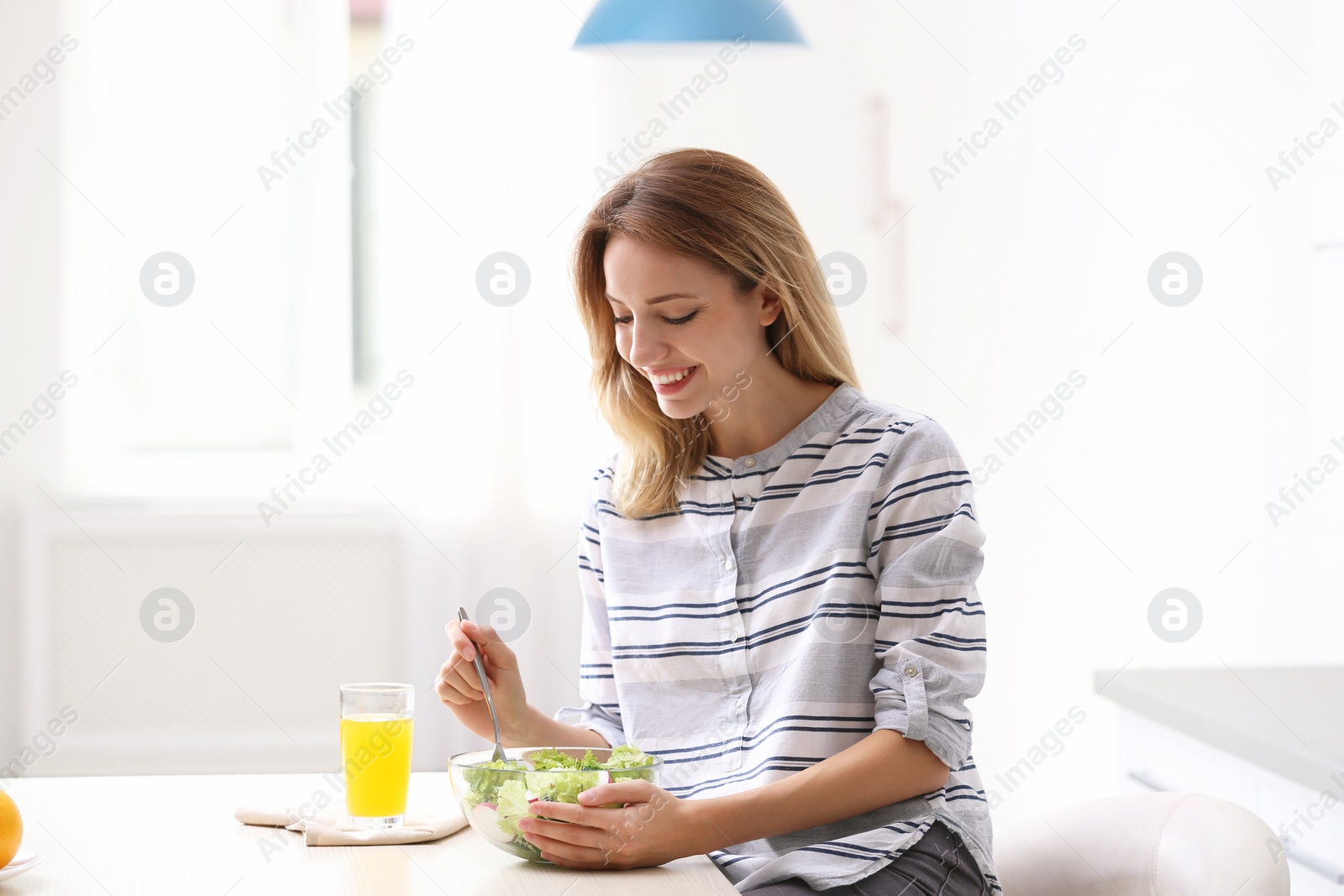 Photo of Woman eating vegetable salad in kitchen. Healthy diet