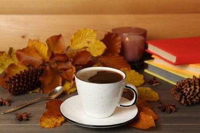 Composition with cup of hot coffee and autumn leaves on wooden table