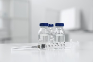 Syringe with vials of medicine on white table