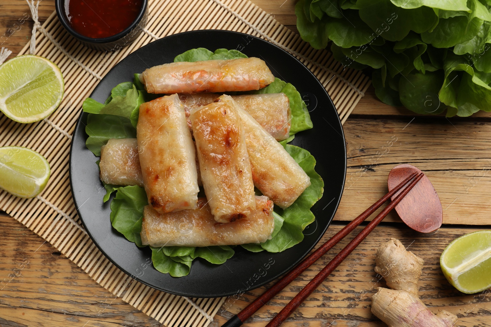 Photo of Tasty fried spring rolls served on wooden table, flat lay