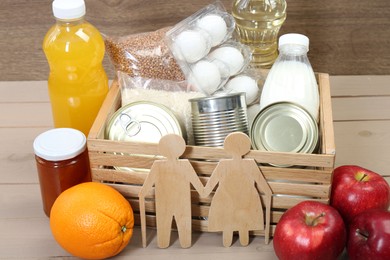 Photo of Humanitarian aid for elderly people. Different donation food and figures of senior couple on wooden table