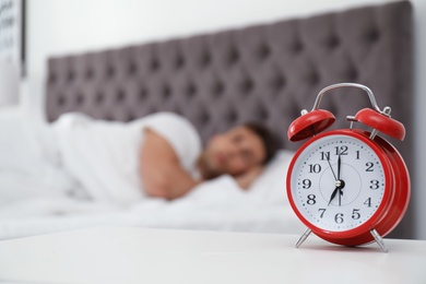 Analog alarm clock and blurred man on background. Time of day