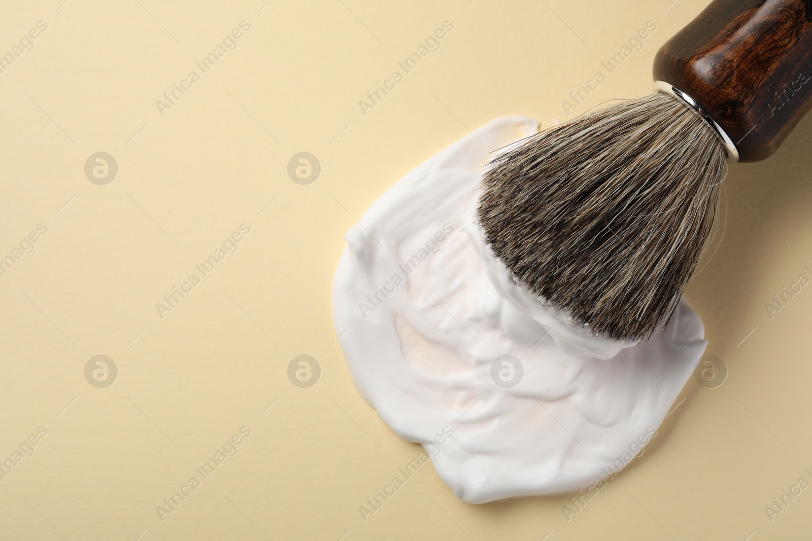 Photo of Brush with shaving foam on beige background, top view. Space for text