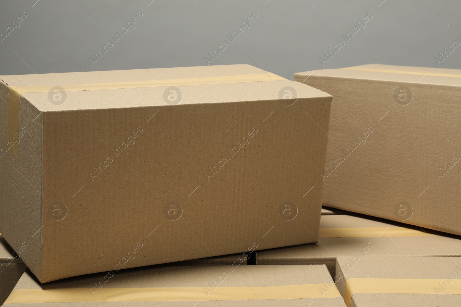 Photo of Many closed cardboard boxes with tape on light grey background