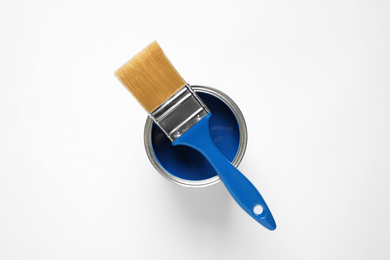 Photo of Can of paint and brush on white background, top view. Color of the year 2020 (Classic blue)