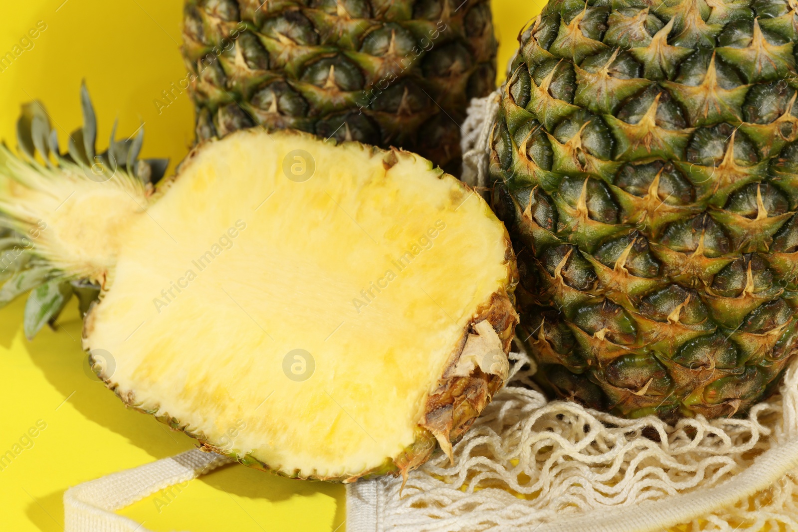 Photo of Whole and cut ripe pineapples on yellow background, closeup