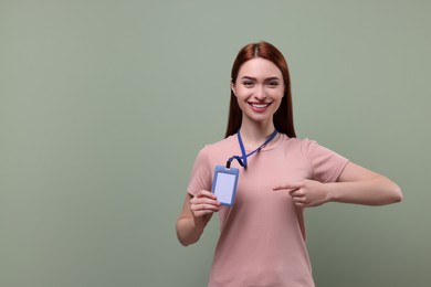 Photo of Smiling woman pointing at vip pass badge on pale green background, space for text