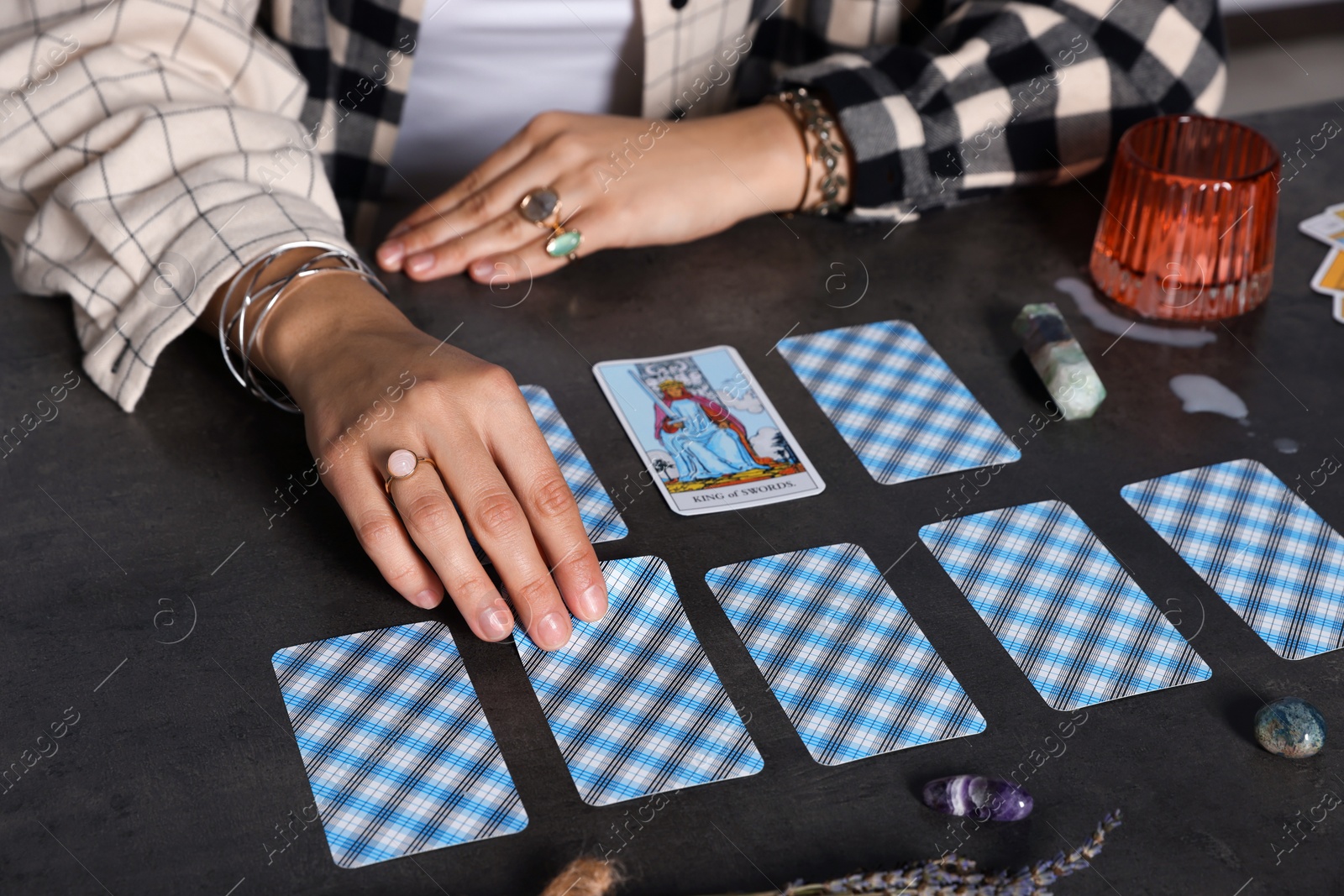 Photo of Fortune teller predicting future on spread of tarot cards at grey table, closeup