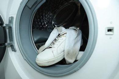 Sneakers with dirty socks in washing machine, closeup