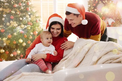 Image of Happy couple with cute baby on sofa in room decorated for Christmas. Magical festive atmosphere