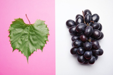 Photo of Fresh ripe juicy grapes and green leaf  on color background, top view