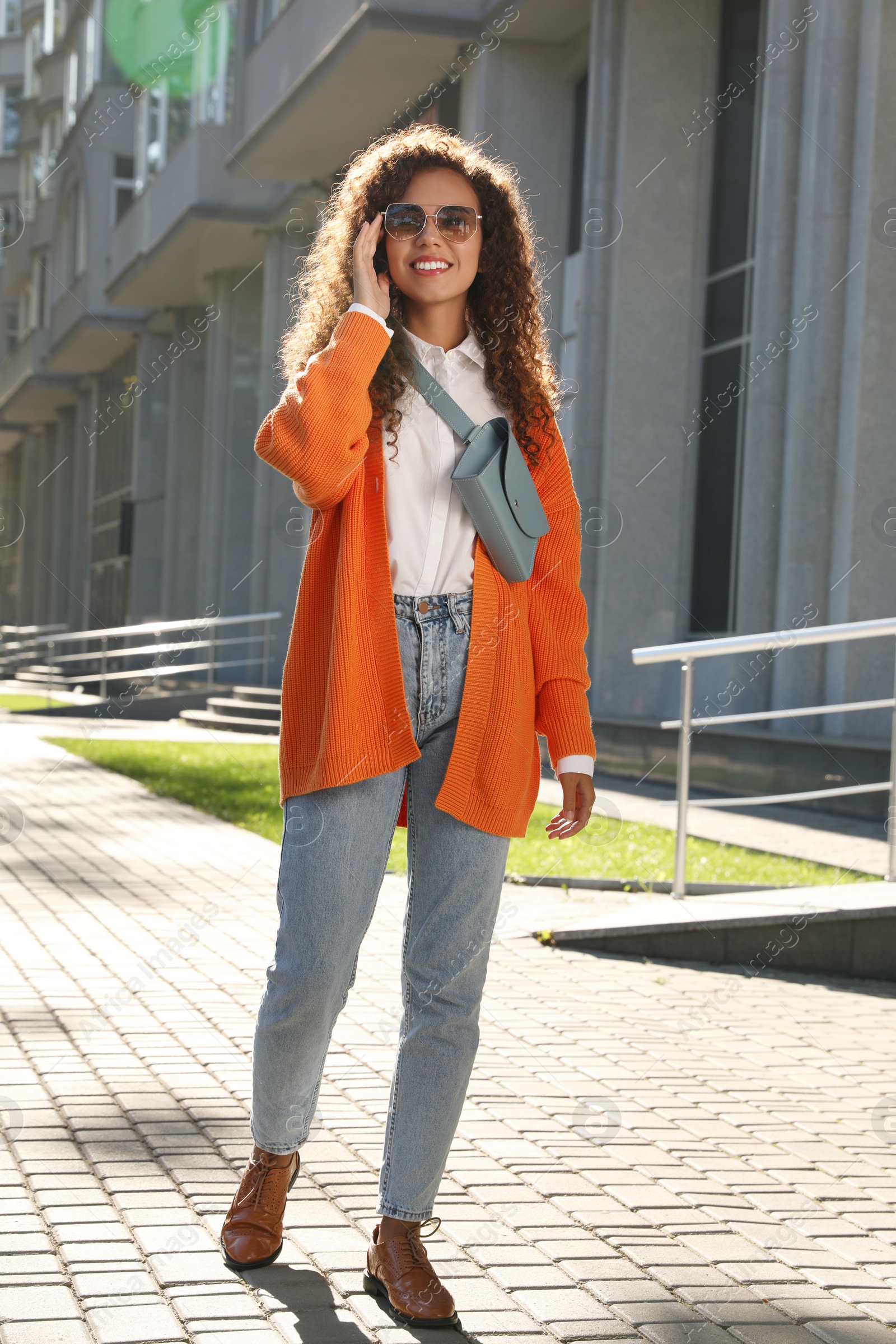 Photo of Beautiful African American woman with stylish waist bag on city street