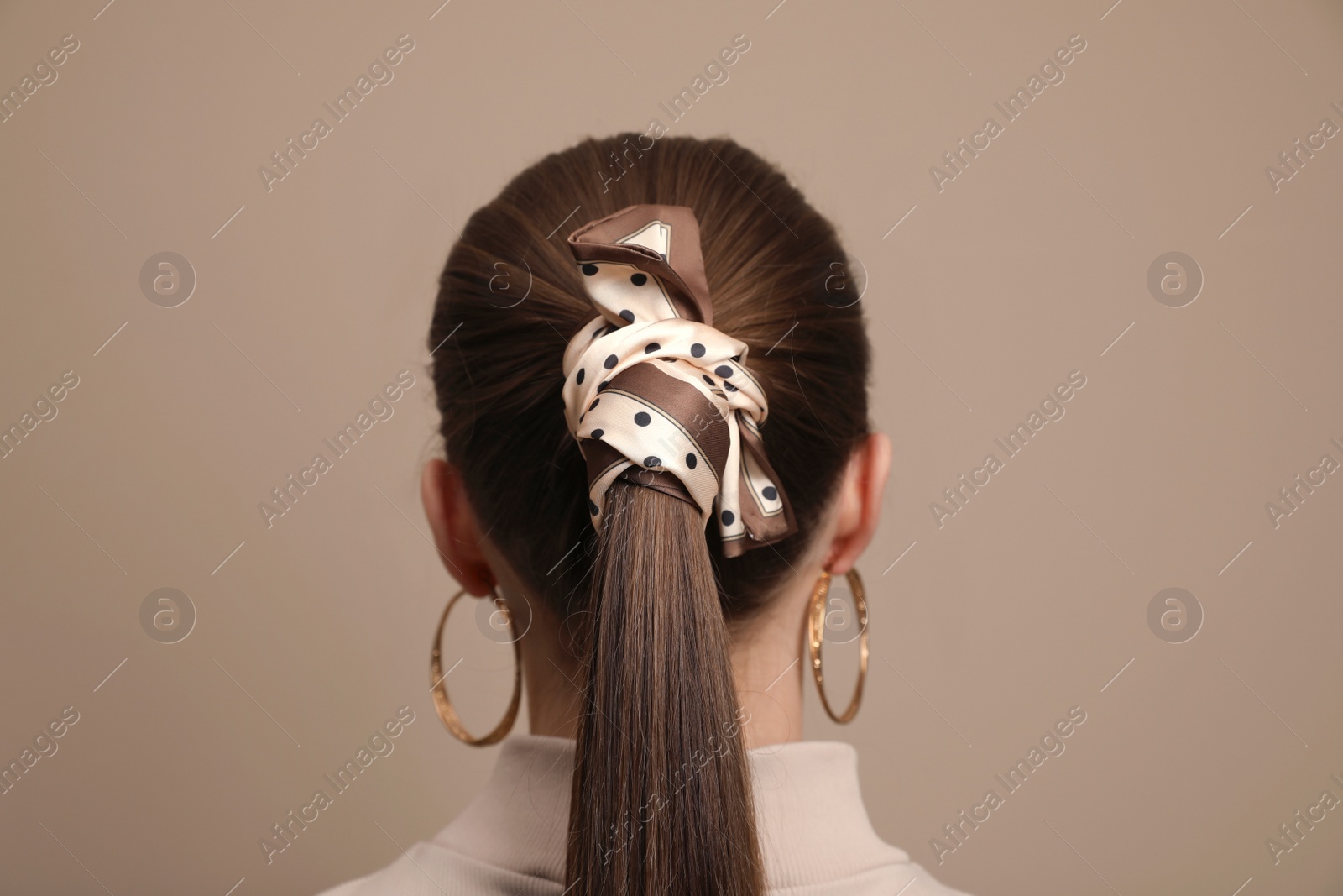 Photo of Young woman with stylish bandana on beige background, back view