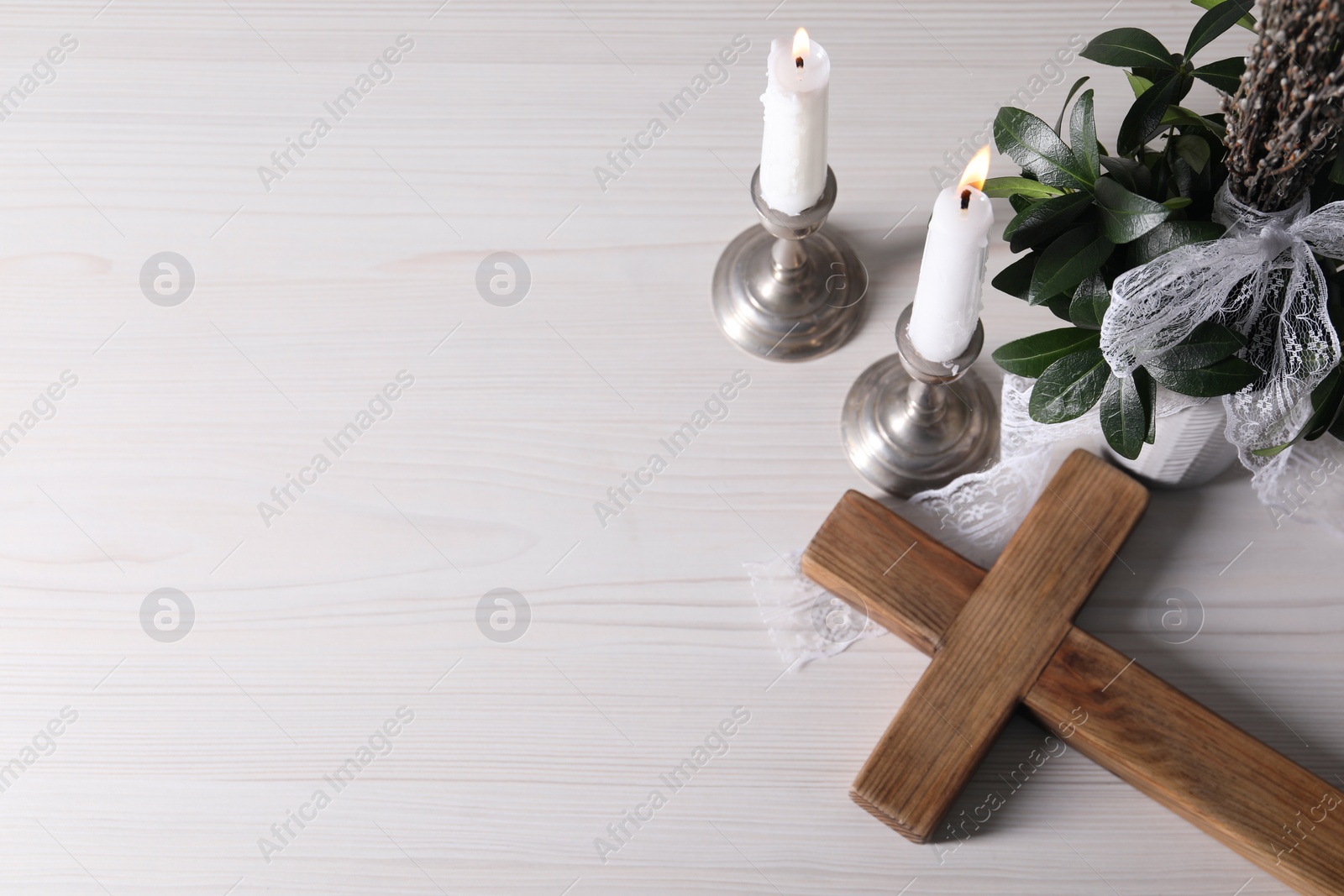 Photo of Burning candles, bouquet with willow branches and cross on white wooden table, flat lay. Space for text