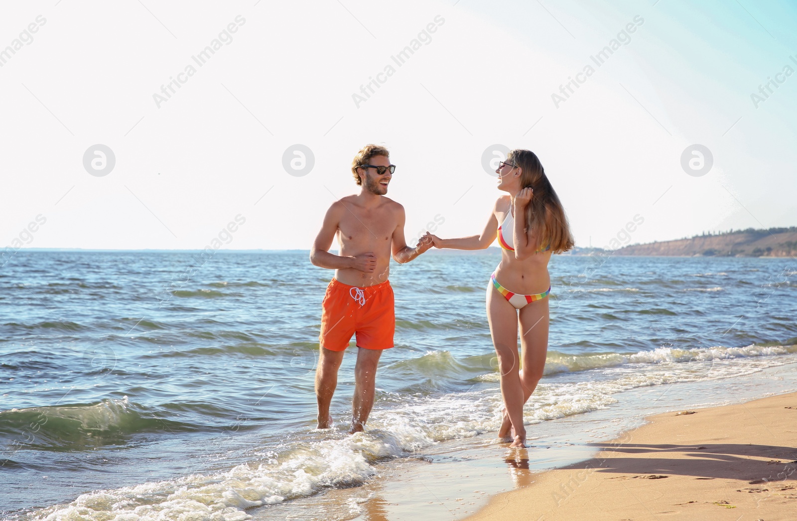 Photo of Happy young couple in beachwear spending time together on seashore