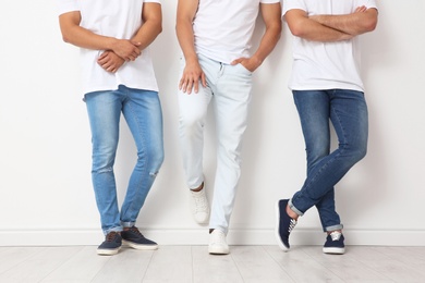 Photo of Group of young men in jeans near light wall