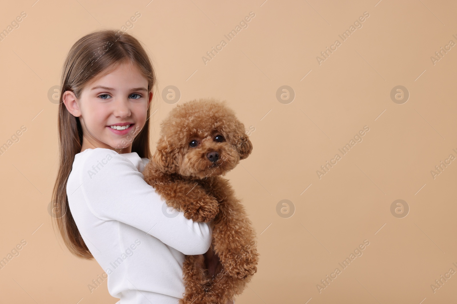 Photo of Little child with cute puppy on beige background, space for text. Lovely pet