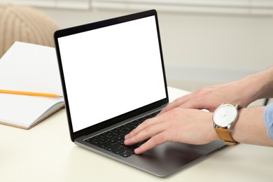 Photo of Man working with laptop at white table indoors, closeup