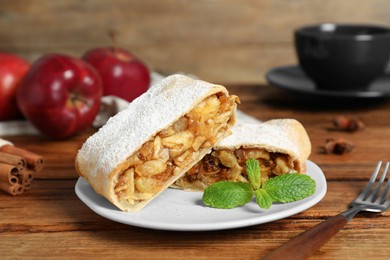 Photo of Delicious strudel with apples, nuts and raisins on wooden table