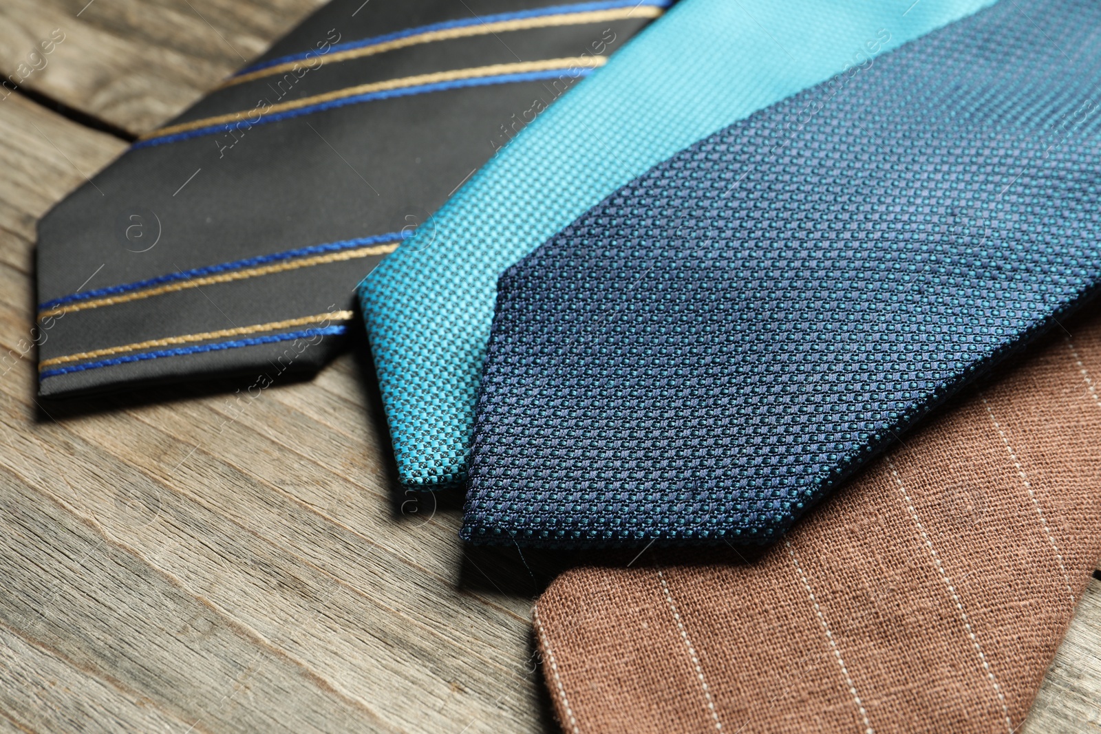 Photo of Different neckties on light wooden table, closeup