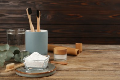 Composition with tooth powder and eucalyptus on wooden table, space for text