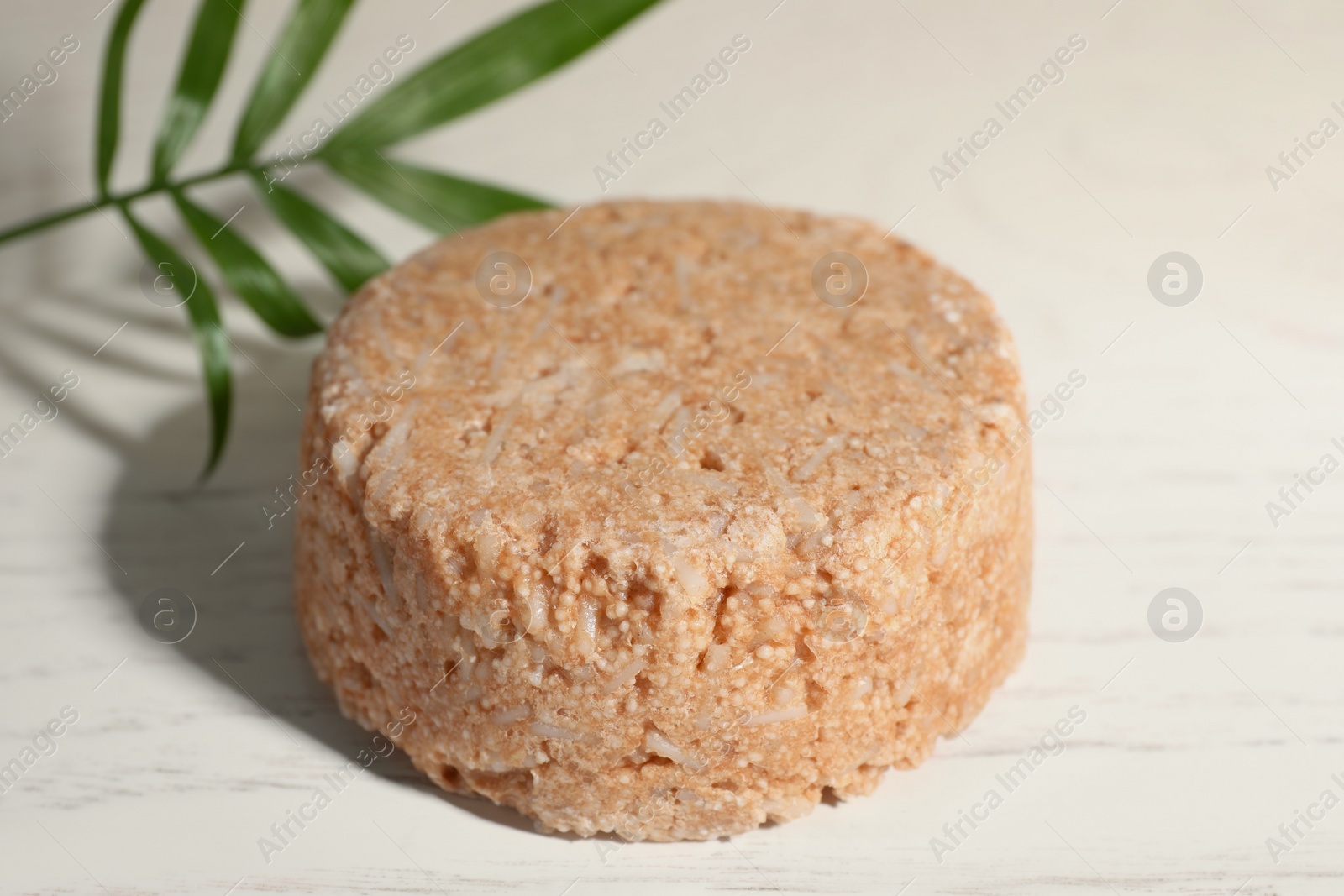 Photo of Solid shampoo bar on white wooden table, closeup