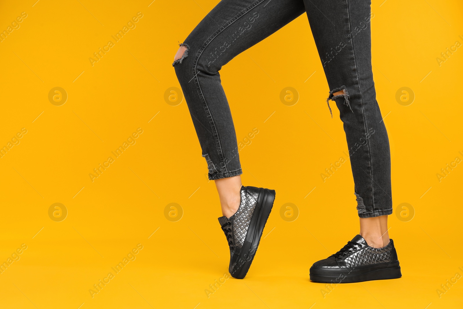 Photo of Woman wearing stylish shoes on yellow background, closeup