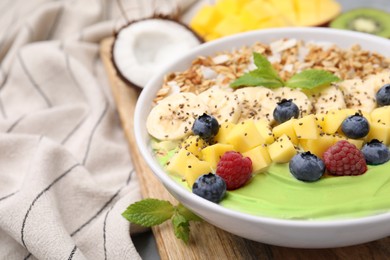 Photo of Tasty matcha smoothie bowl served with fresh fruits and oatmeal on table, closeup with space for text. Healthy breakfast
